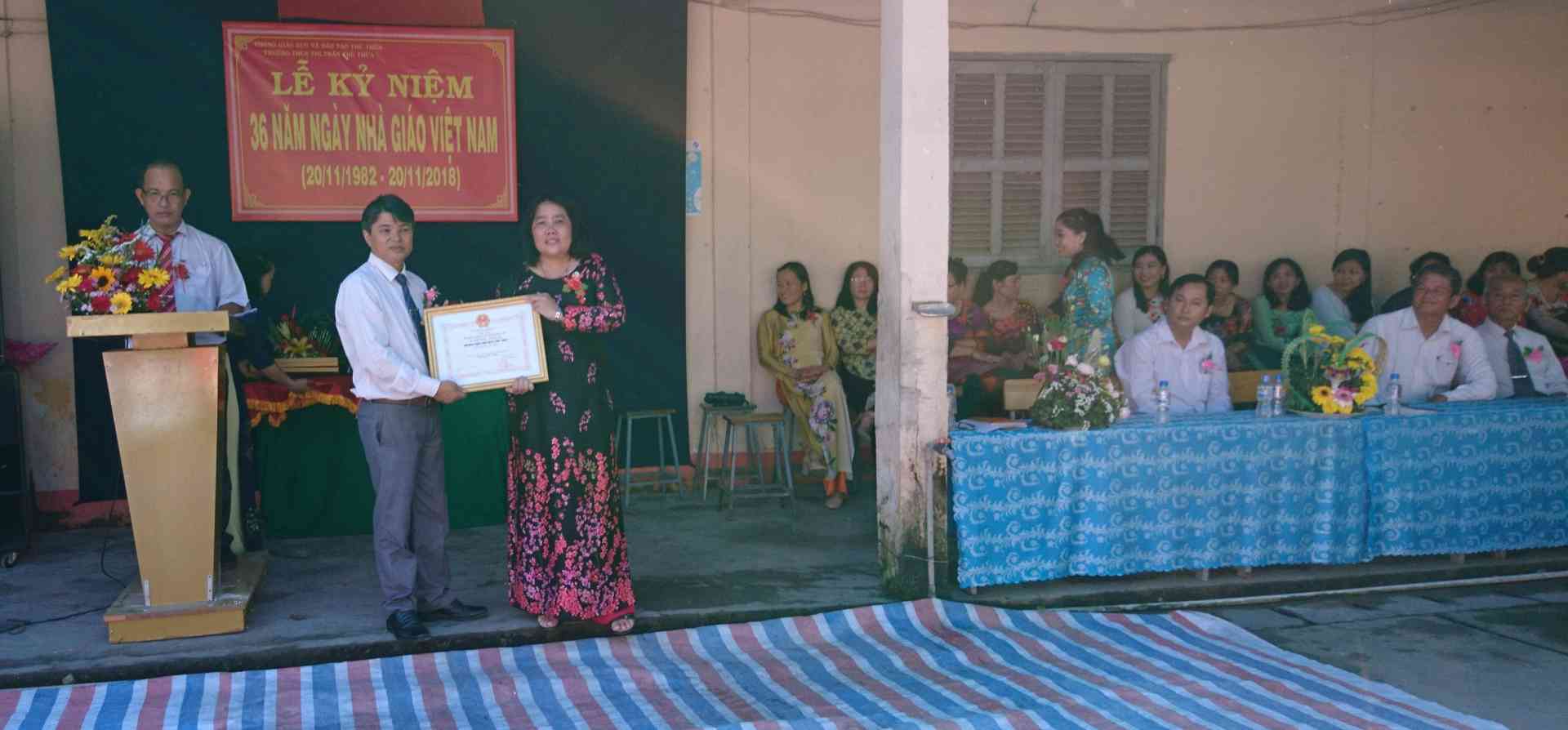 Trưởng Phòng GD&ĐT huyện ( bìa trái) trao bằng khen của UBND Tỉnh cho tập thể trường THCS Thị trấn Thủ Thừa